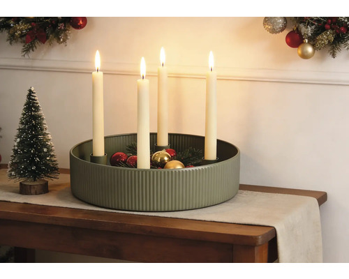 Décoration de Noël festive avec une coupe en métal vert rainuré, quatre bougies allumées, des boules de Noël et un petit sapin décoratif.