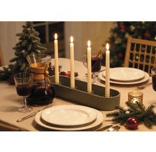 Bougeoir de l'Avent avec quatre bougies allumées sur une table de Noël dressée avec de la vaisselle et des décorations.