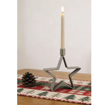 Chandelier en forme d'étoile en métal nervuré avec une bougie allumée, à côté d'une pomme de pin sur un chemin de table festif.