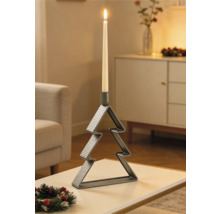 Bougeoir en métal en forme de sapin de Noël avec une bougie allumée sur une table dans un salon décoré pour les fêtes.
