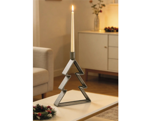 Bougeoir en métal en forme de sapin de Noël avec une bougie allumée sur une table dans un salon décoré pour les fêtes.