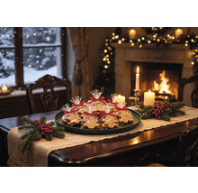 Table en bois décorée pour les fêtes avec des pains d épices emballés, des branches de sapin, des baies rouges et des bougies devant une cheminée.