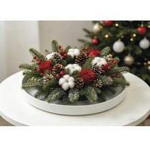 Composition de Noël festive avec des branches de sapin, des roses rouges, des fleurs de coton et des pommes de pin sur un plateau blanc.