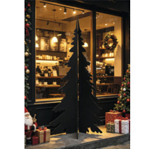 Silhouette de sapin de Noël noire en bois ou métal devant une vitrine avec décorations de Noël et cadeaux.