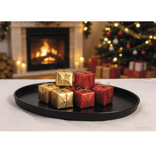 Petites boîtes cadeaux dorées et rouges avec rubans dorés sur un plateau noir devant une cheminée allumée et un sapin de Noël.