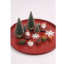 Ensemble de décorations de Noël avec sapins miniatures, figurines de Père Noël, petits cadeaux et flocons de neige sur un plateau rouge.