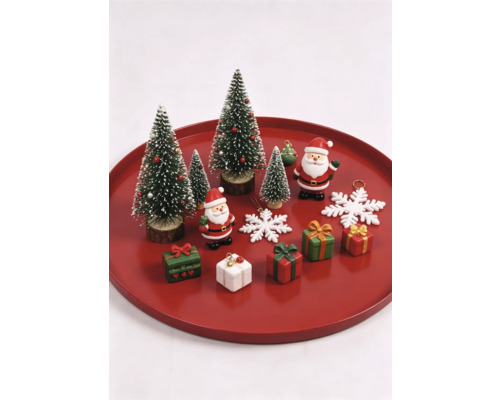 Ensemble de décorations de Noël avec sapins miniatures, figurines de Père Noël, petits cadeaux et flocons de neige sur un plateau rouge.