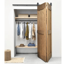 Porte coulissante pliante en bois de style grange devant un dressing organisé avec un système de rails noirs.