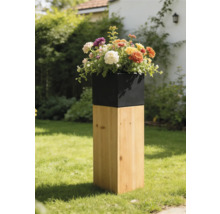 Jardinière moderne avec socle carré en bois et insert noir, garnie de fleurs colorées dans un paysage de jardin.