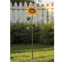 Metall-Gartenstecker in Sonnenblumenform in einem hellen Garten auf grünem Rasen vor Büschen und einem weißen Zaun.