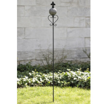 Tige de jardin décorative en métal avec boule en céramique, élément en forme de cœur et fleur de lys devant un mur en pierre.