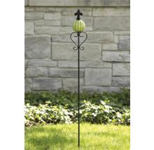 Tuteur de jardin en métal noir avec boule en céramique nervurée verte, volutes décoratives et pointe fleur de lys dans un jardin.