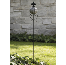 Tuteur de jardin avec fleur de lys, boule nervurée et décoration en forme de cœur dans un jardin lumineux.