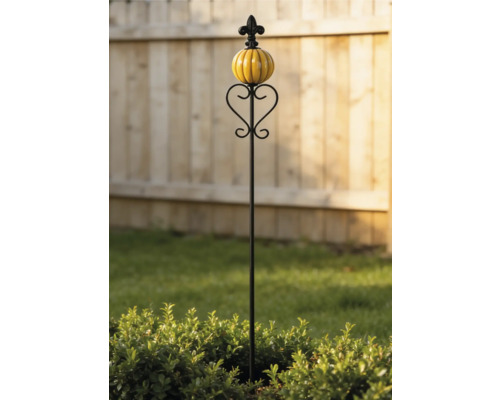 Tuteur de jardin décoratif en métal avec une boule en céramique jaune et des ornements en forme de cœur devant une clôture en bois.