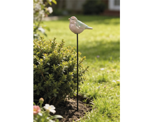 Pique de jardin avec oiseau en céramique sur tige en métal noir à côté d'un arbuste dans le jardin.