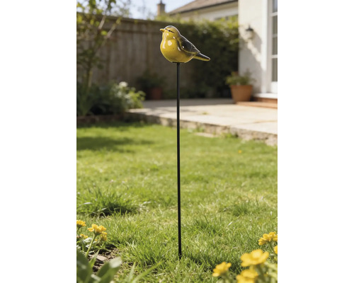 Gartenstecker mit gelbem Vogel aus Keramik auf einem schwarzen Metallstab in einem sonnigen Garten mit Rasen.