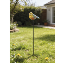 Pic de jardin avec une figurine d'oiseau sur une longue tige métallique, placé dans une pelouse avec un jardin en arrière-plan.