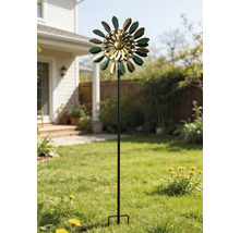 Éolienne cinétique en métal vert et or avec des feuilles sur un support haut dans un jardin ensoleillé sur la pelouse.