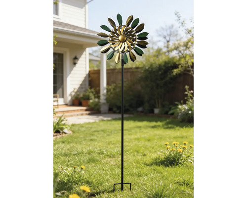 Éolienne cinétique en métal vert et or avec des feuilles sur un support haut dans un jardin ensoleillé sur la pelouse.
