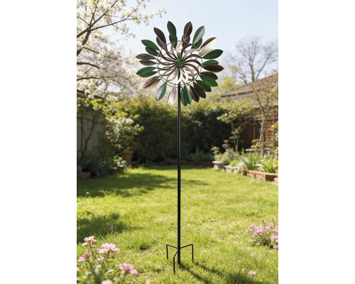 Dekoratives Windspiel aus Metall in Blätterform auf einem schwarzen Stab in einem hellen, gepflegten Garten.
