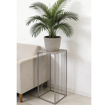 Support à plantes carré en métal gris avec barres verticales, avec une plante verte en pot à côté d'un canapé.