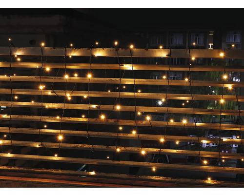 Warmweiß leuchtende LED Lichterkette an einem Geländer im Außenbereich bei Dunkelheit.