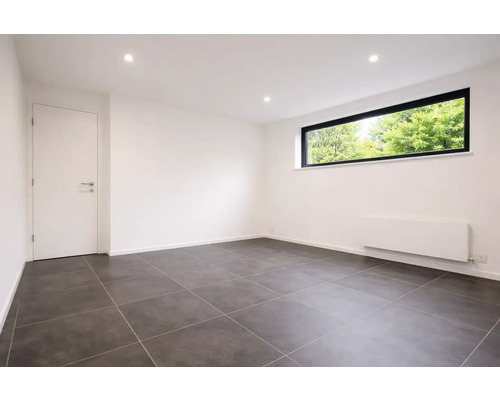 Pièce vide moderne avec des carreaux de sol gris foncé, des murs blancs, une fenêtre à cadre noir et une porte intérieure blanche.
