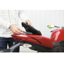 Installation d'un traceur GPS dans le compartiment de rangement sous la selle d'une moto.