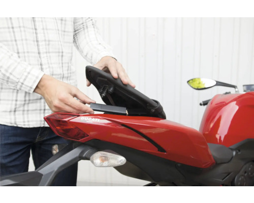 Installation d'un traceur GPS dans le compartiment de rangement sous la selle d'une moto.