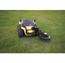 Robot tondeuse jaune avec entraînement par chenilles et bras de coupe latéral sur une pelouse.