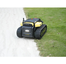 Robot de jardin autonome Yarbo avec chenilles sur une pelouse à côté d'un chemin.