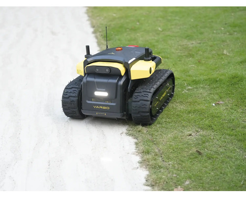 Robot de jardin autonome Yarbo avec chenilles sur une pelouse à côté d'un chemin.