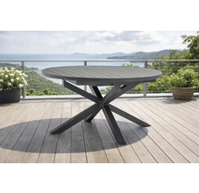 Table de jardin ronde moderne en métal avec un piètement en étoile sur une terrasse claire avec vue sur la mer.