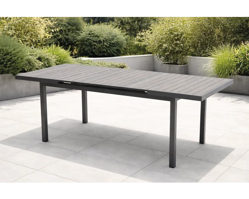 Table de jardin moderne et extensible en aluminium anthracite avec structure à lattes sur une terrasse carrelée claire dans un jardin.