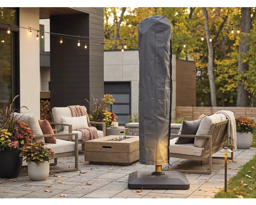 Graue Schutzhülle für Ampelschirm auf einer modern eingerichteten Terrasse mit Loungemöbeln, Feuertisch und Lichterkette.