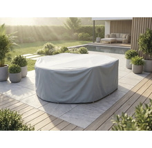 Graue Schutzhülle für eine runde Gartenmöbelgruppe auf einer hellen Steinterrasse in einem gepflegten Garten mit Pool und Pflanzen.