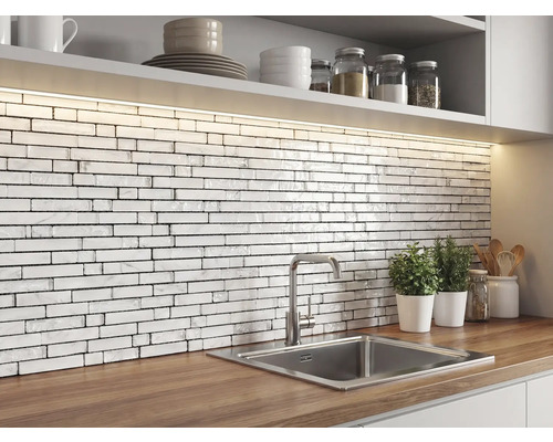 Küche mit einem Fliesenspiegel aus weißen Mosaikfliesen in Ziegeloptik mit Marmorstruktur, Holz-Arbeitsplatte, Edelstahlspüle und LED-Beleuchtung.