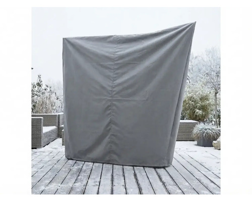 Housse de protection grise pour un fauteuil de plage sur une terrasse en bois enneigée dans le jardin.
