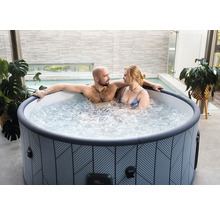 Couple se détendant dans un spa gonflable rond à motifs géométriques sur une terrasse moderne.