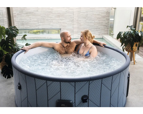 Couple se détendant dans un spa gonflable rond à motifs géométriques sur une terrasse moderne.
