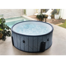 Bain à remous gonflable rond avec motif géométrique et eau bouillonnante sur une terrasse lumineuse à côté d une piscine et d un pont en bois.