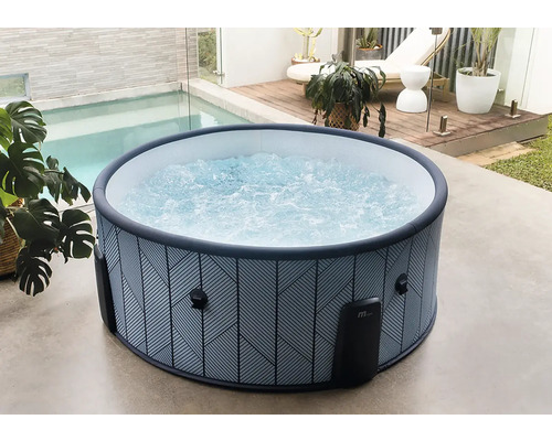 Bain à remous gonflable rond avec motif géométrique et eau bouillonnante sur une terrasse lumineuse à côté d une piscine et d un pont en bois.