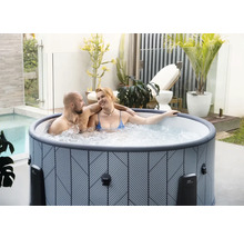 Jacuzzi gonflable avec motif géométrique sur une terrasse lumineuse avec des plantes et un couple.