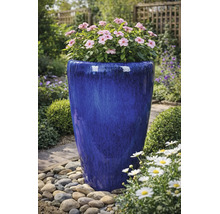 Grand pot de fleurs en céramique émaillée bleue avec des fleurs roses dans un jardin avec des galets.