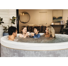 Une famille se détend dans un spa gonflable rond avec de l eau bouillonnante dans une pièce de vie chaleureuse.