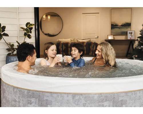 Une famille se détend dans un spa gonflable rond avec de l eau bouillonnante dans une pièce de vie chaleureuse.