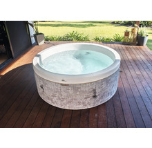 Jacuzzi rond avec paroi extérieure à motifs gris sur une terrasse en bois dans un jardin.