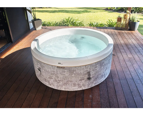 Jacuzzi rond avec paroi extérieure à motifs gris sur une terrasse en bois dans un jardin.