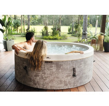 Spa gonflable MSpa avec deux personnes sur une terrasse en bois dans un jardin lumineux.
