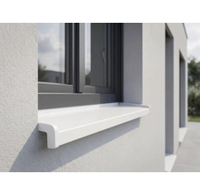 Appui de fenêtre extérieur blanc monté sur une façade claire sous un cadre de fenêtre sombre.